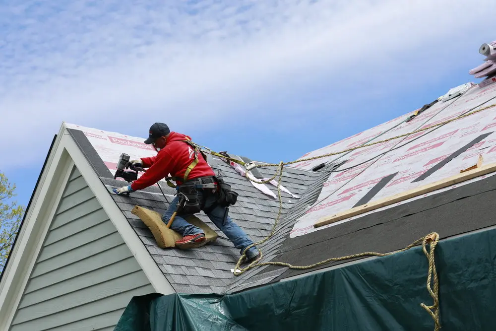Guy in red jacket fixing roof in Texas - TSG Roofing